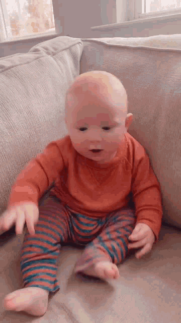a baby is sitting on a couch in a living room .