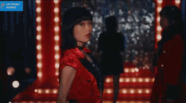 a girl in a red jacket stands in front of a sign that says up-front works
