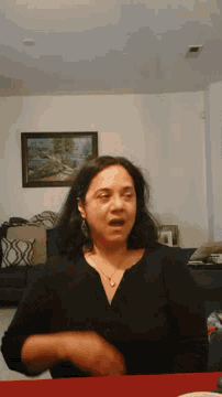a woman in a black shirt is sitting in a living room