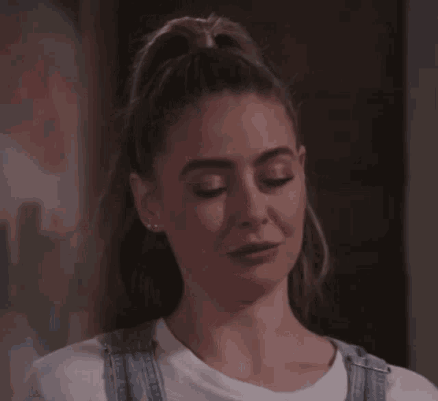 a woman with a ponytail and overalls is smiling