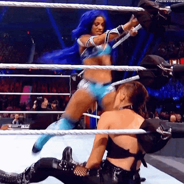 a woman with blue hair is wrestling another woman in a wrestling ring