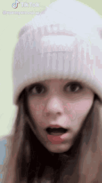 a woman wearing a white beanie has a surprised look on her face ..