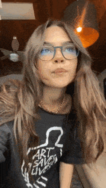 a woman wearing glasses and a t-shirt that says art saves lives .