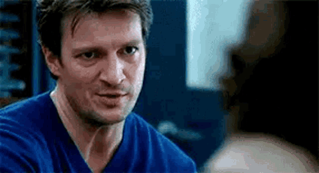 a close up of a man wearing a blue shirt talking to another man .