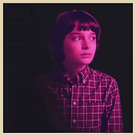 a young boy wearing a plaid shirt is looking at the camera .
