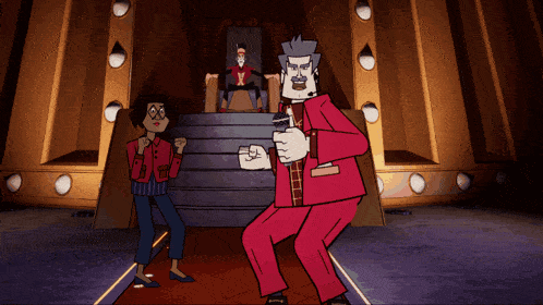 a man in a red suit is holding a microphone while a woman stands behind him