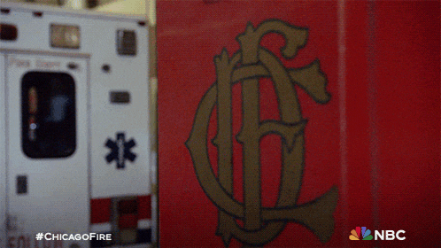 a white ambulance is parked next to a red wall with the letters nbc on it