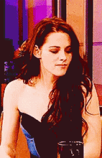 a woman in a black strapless top looks down at something