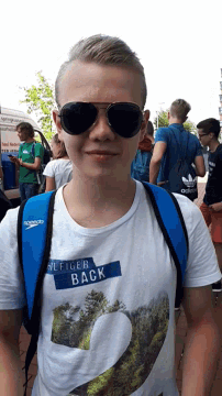 a boy wearing sunglasses and a white shirt that says hilfiger back