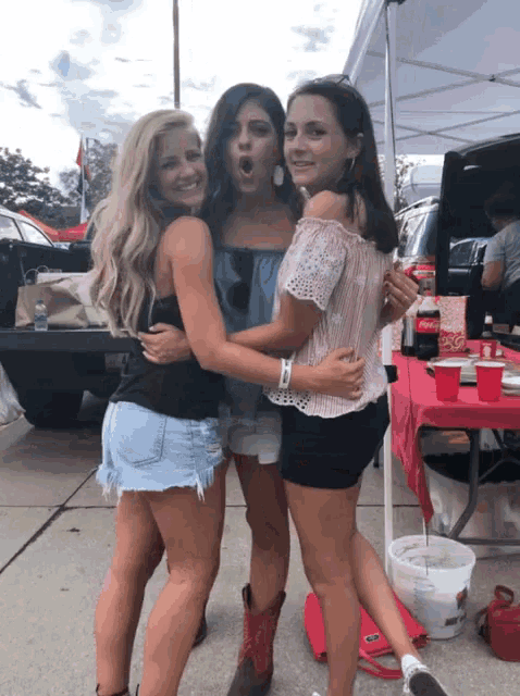 three girls are posing for a picture in front of a red table