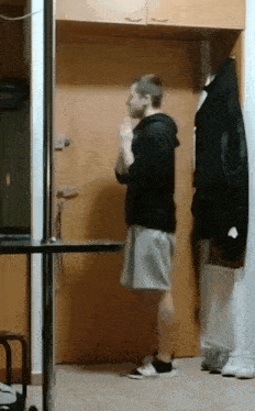 a man in shorts is standing in front of a door with his hands folded