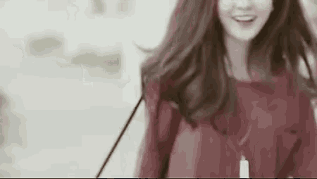 a woman in a red dress is smiling while walking down the street .