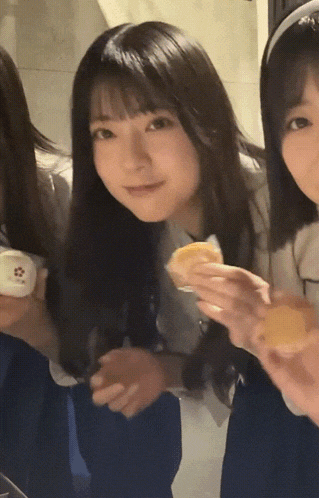 a girl with long black hair is smiling while holding a cupcake
