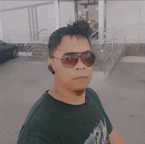 a man wearing sunglasses and a black shirt is standing outside of a building