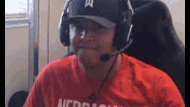a man wearing headphones and a hat is sitting in a chair
