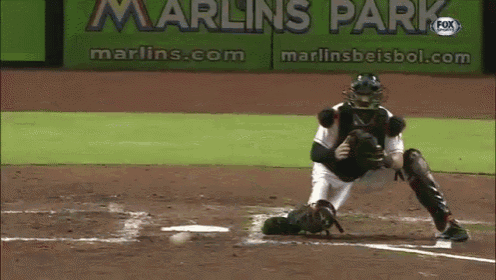 a baseball player catches a ball in front of a sign that says marlins park