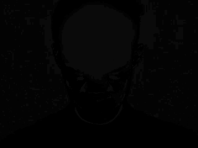 a black and white photo of a man 's face in the dark