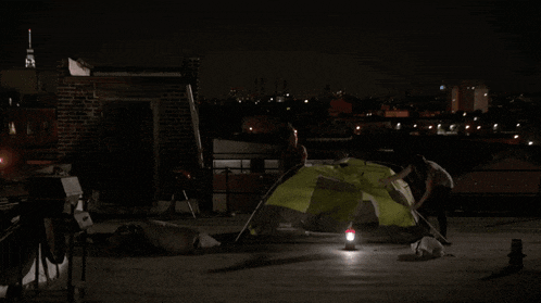 a man is setting up a tent on the roof of a building