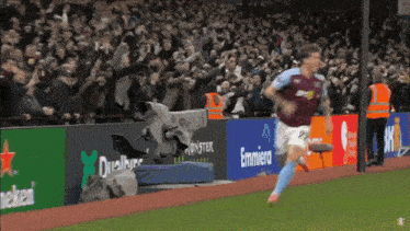 a soccer player is running on the field in front of a banner that says emmiera