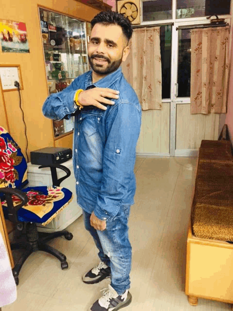 a man in a denim shirt is standing in front of a chair