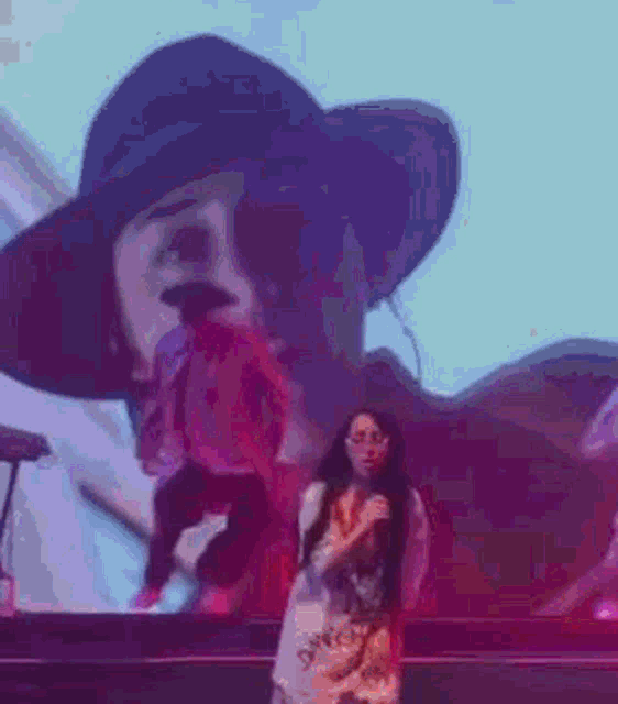 a woman is singing into a microphone on a stage in front of a giant screen .