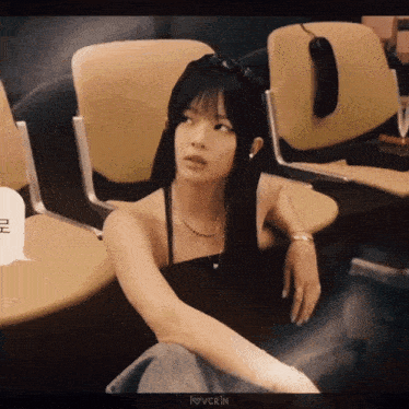 a woman in a black top sits in a row of chairs with a speech bubble that says i love vcrin
