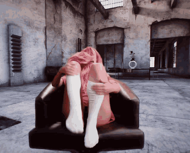 a woman with pink hair is sitting in a chair with her legs crossed