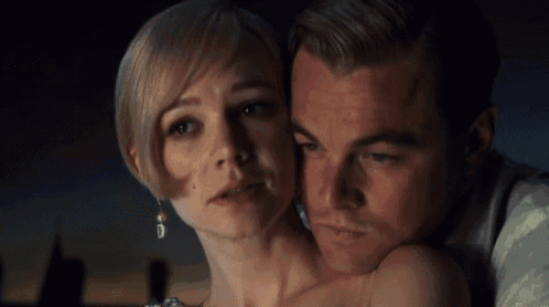 a man and a woman are looking at each other with the man 's arm around the woman 's shoulder