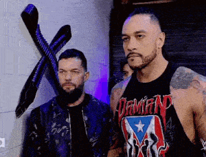 two men are standing next to each other in front of a brick wall in a room .