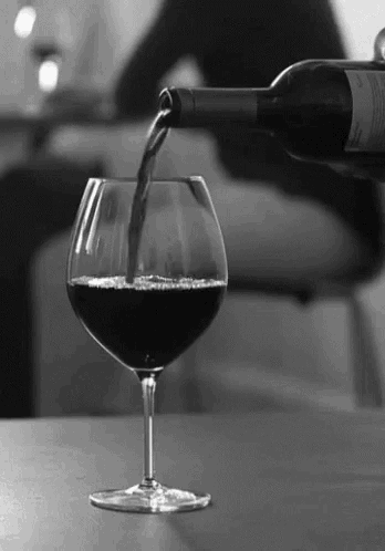 a bottle of wine is poured into a glass on a table