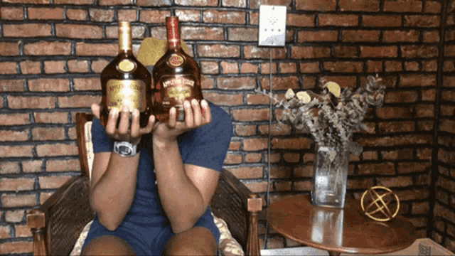 a man is holding two bottles of crown royal