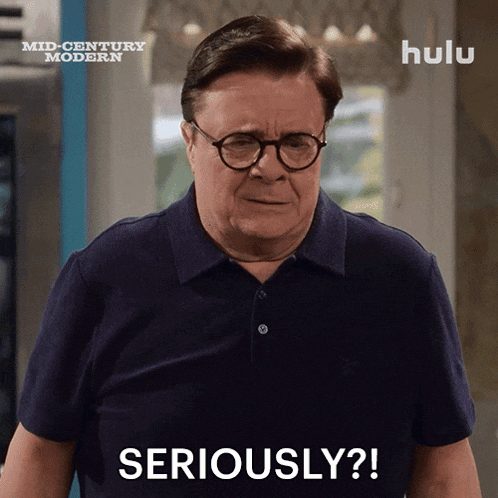 a man wearing glasses and a blue shirt with the words seriously on it