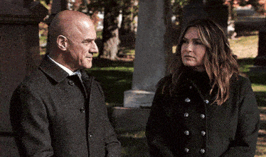 a man and a woman are standing in a cemetery