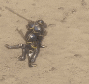 a statue of a man in armor is laying on the ground holding a stick .
