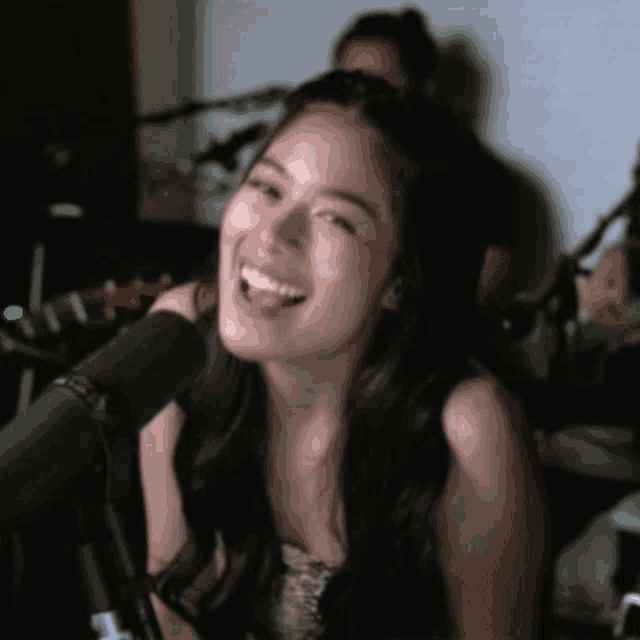a woman is smiling in front of a microphone with a green light on it