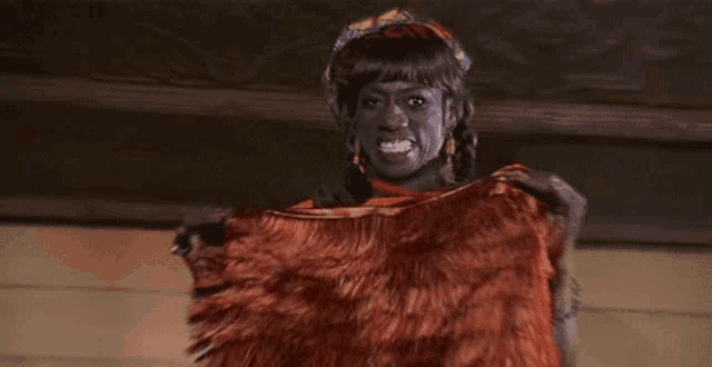 a man with black paint on his face is holding a red fur coat .