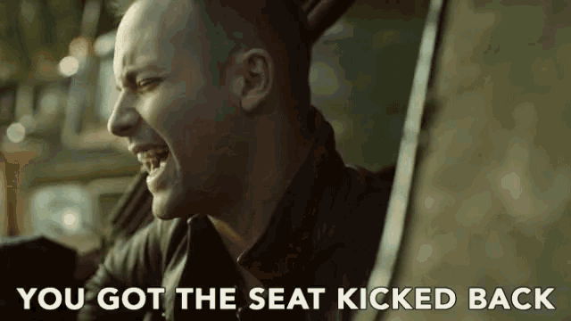 a man sitting in a car with the words " you got the seat kicked back " below him