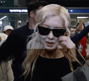 a woman wearing sunglasses stands in front of a shopping spot