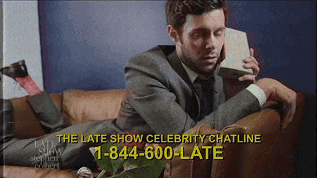 a man laying on a couch talking on a phone with the late show celebrity chatline number
