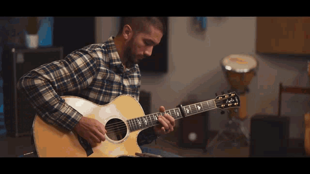 a man in a plaid shirt is playing a guitar