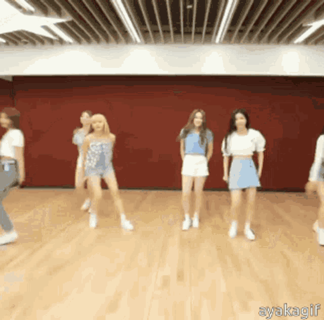 a group of girls are dancing together in a room with a red wall .