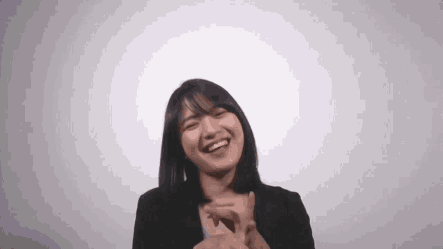 a young woman is smiling and clapping her hands against a white background .