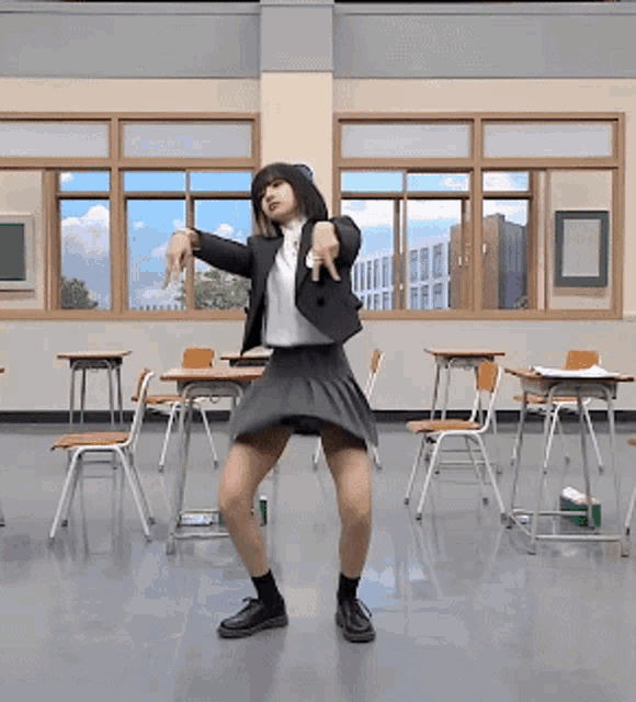 a girl in a skirt and jacket is dancing in a classroom with desks and chairs