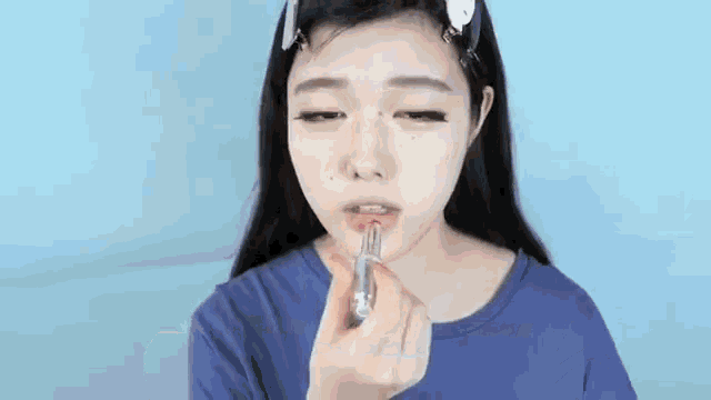 a woman is applying lipstick to her lips with a brush .