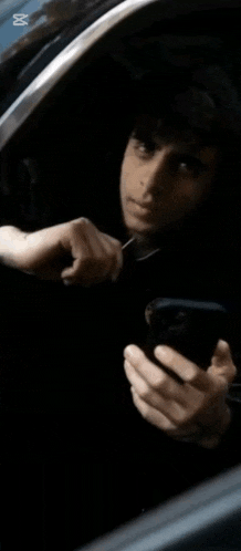 a man in a car is looking at his phone and the word yazar is on the bottom right