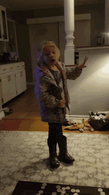 a little girl standing in a living room with her hands up