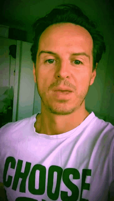 a man wearing a choose shirt looks at the camera