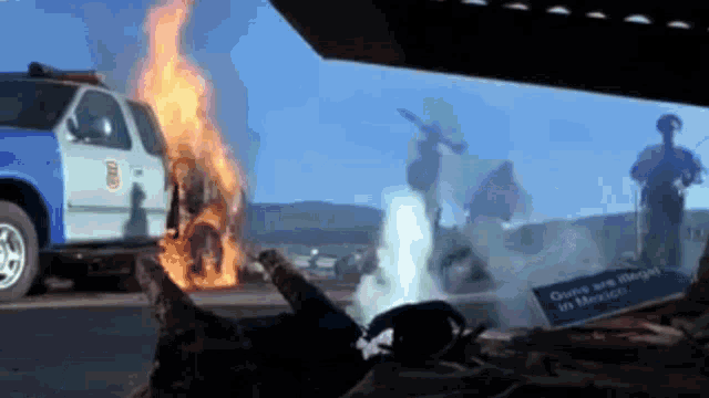 a man is laying on the ground in front of a truck that is on fire