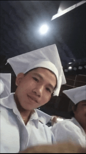 a man in a white cap and gown poses for a photo