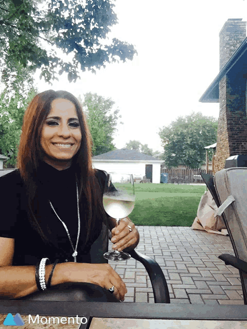a woman sitting in a chair holding a glass of wine with the word momento in the corner